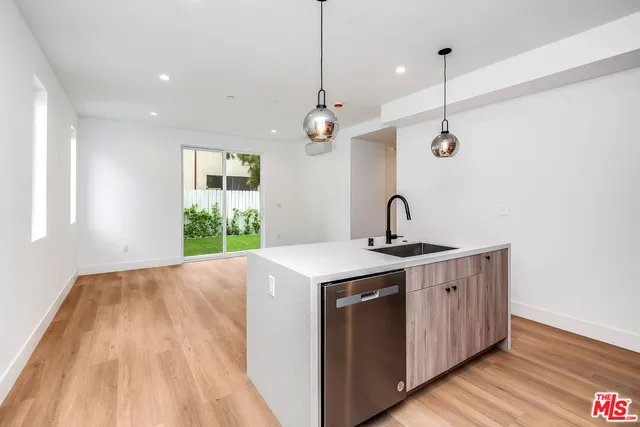 a kitchen with kitchen island a sink appliances and a wooden floor