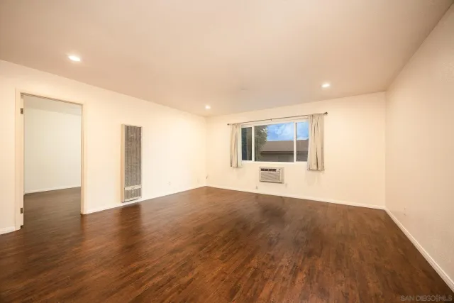 a view of an empty room with a window and wooden floor