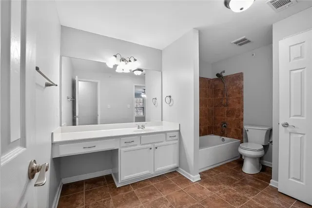 a spacious bathroom with a double vanity sink a toilet a mirror and shower