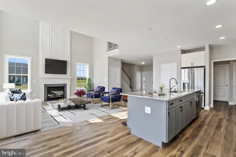 a living room with furniture a fireplace and a dining table with wooden floor