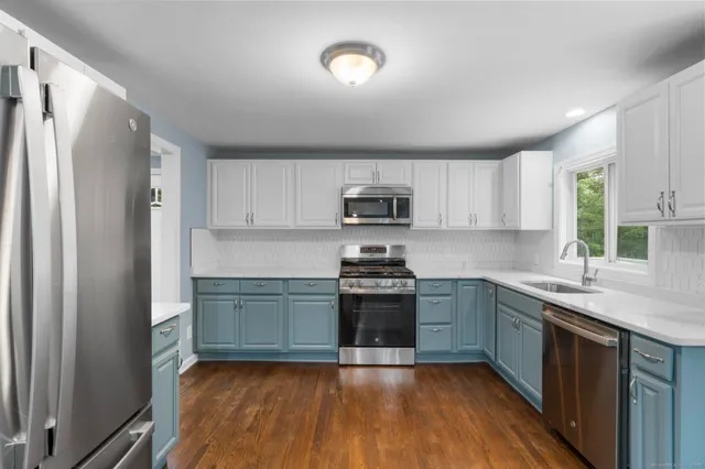 a kitchen with stainless steel appliances granite countertop a stove top oven a sink and dishwasher with wooden floor