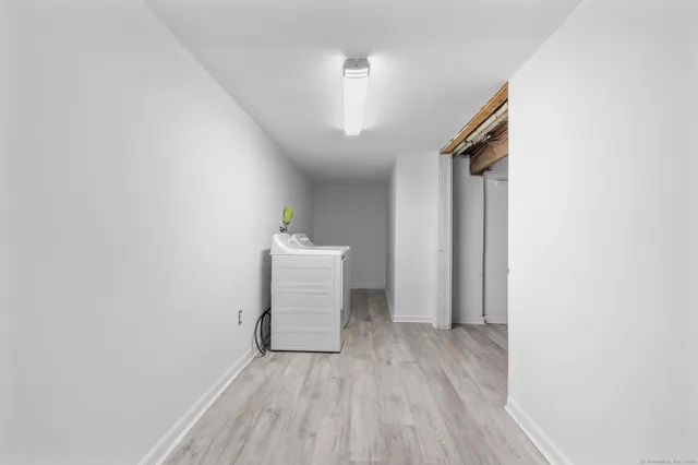 a view of a hallway with wooden floor and a bathroom
