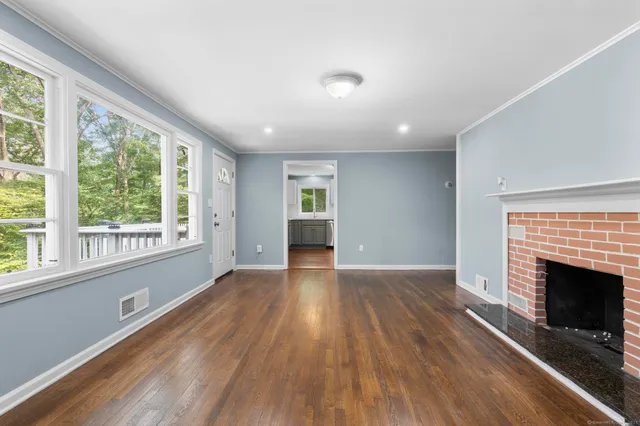 an empty room with wooden floor fireplace and windows