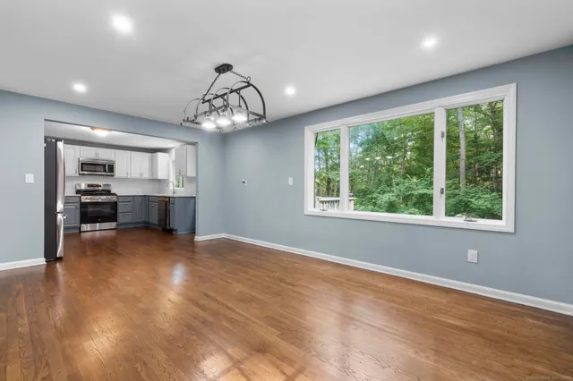 a view of empty room with wooden floor and kitchen view