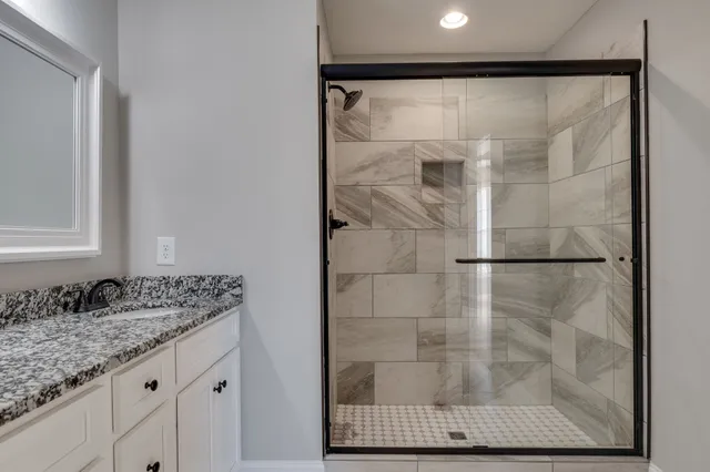 a bathroom with a granite countertop shower sink and mirror