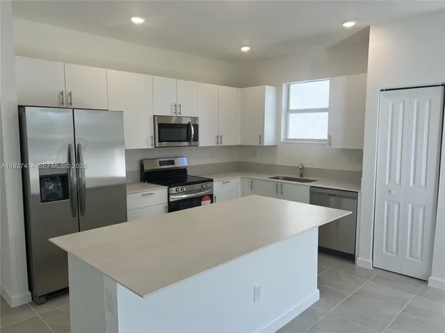 a large kitchen with a large counter top stainless steel appliances and cabinets