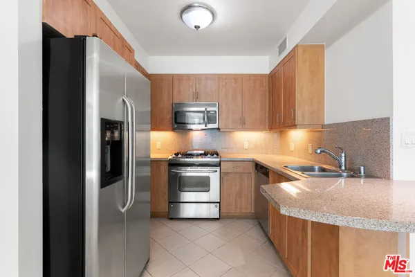 a kitchen with stainless steel appliances granite countertop a refrigerator sink and stove