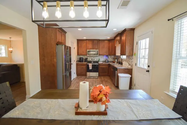 a living room with stainless steel appliances furniture a rug and a window