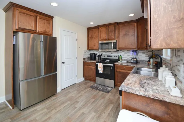 a kitchen with stainless steel appliances granite countertop a refrigerator stove top oven and sink