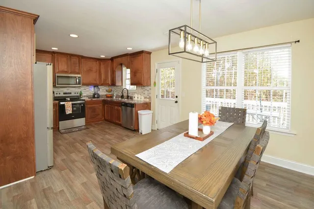 a kitchen with stainless steel appliances granite countertop a stove top oven a refrigerator a sink and dining table with wooden floor