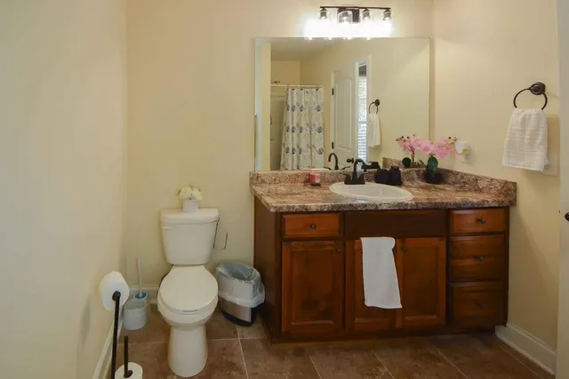 a bathroom with a granite countertop toilet sink and mirror