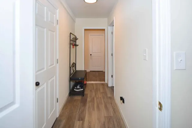 a view of a hallway with wooden floor and a bathroom