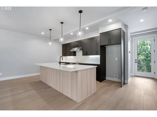 a kitchen with stainless steel appliances kitchen island wooden floors wooden cabinets and entryway