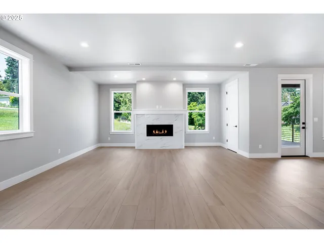 an empty room with windows and fireplace