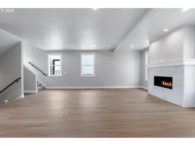 a view of an empty room with wooden floor and a fireplace