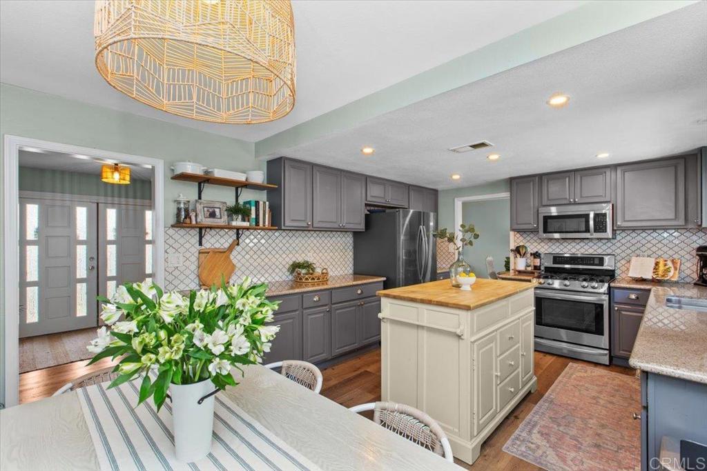1480 Kurtz Street Oceanside, CA 92054 - Photo 13 of 31 a kitchen with stainless steel appliances kitchen island granite countertop a table chairs stove and cabinets