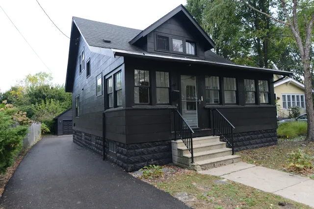 a view of wooden house with a small yard and wooden fence