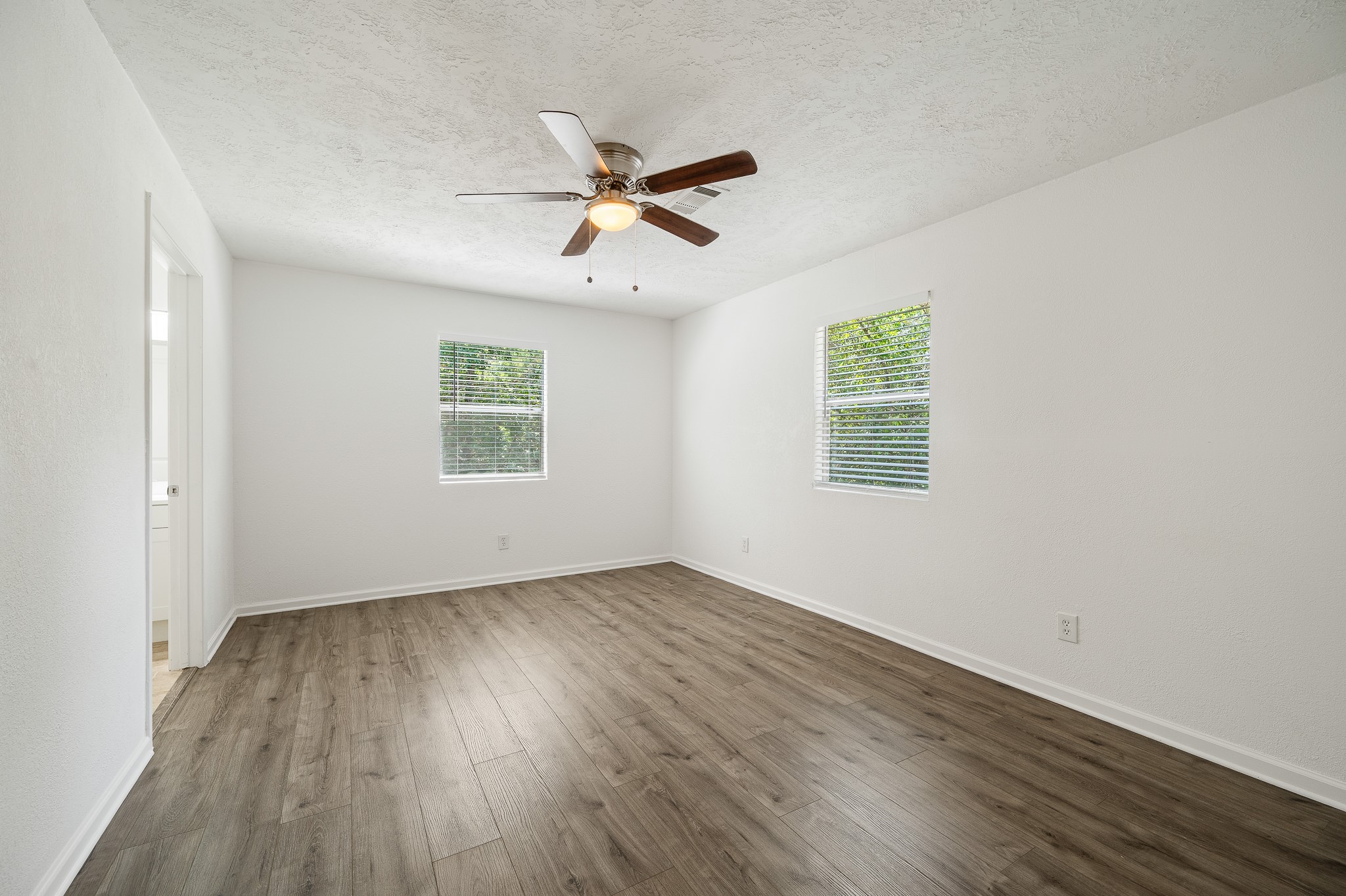 61 Hicks Loop West Cleveland, TX 77328 - Photo 16 of 38 Spacious, light-filled room featuring elegant wood flooring and a ceiling fan, offering a serene and comfortable ambiance.
