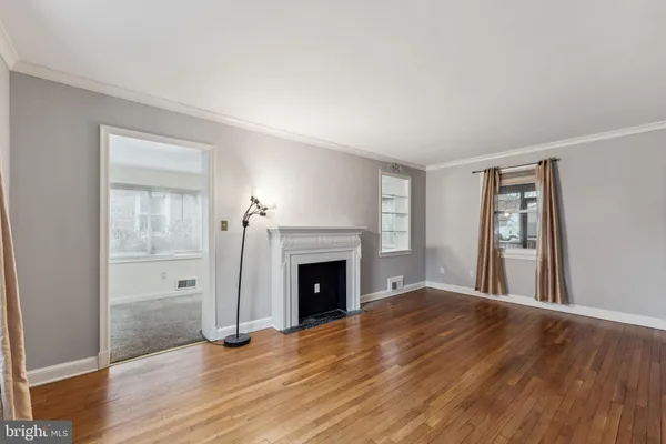 an empty room with wooden floor fireplace and windows