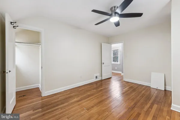 an empty room with wooden floor and a ceiling fan