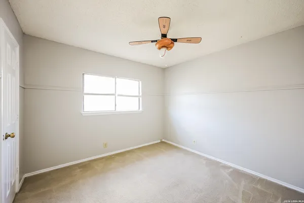 an empty room with a window and a ceiling fan