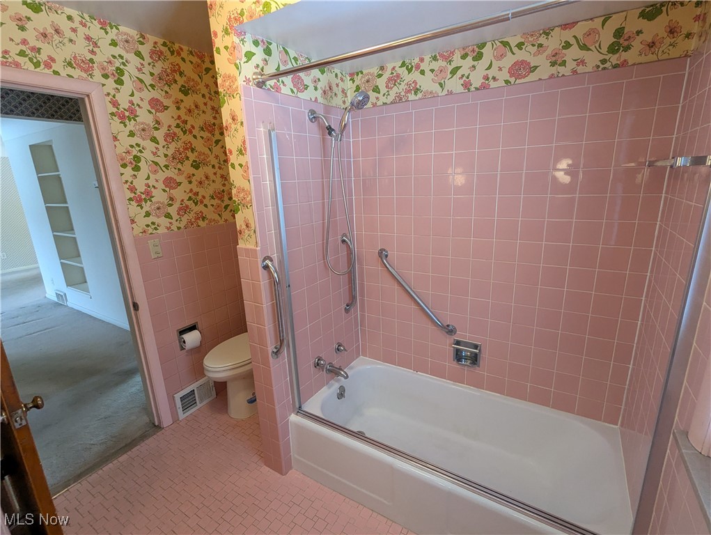 815 East Schaaf Road Independence, OH 44131 - Photo 21 of 36 Bathroom featuring built in shelves, tile patterned flooring, enclosed tub / shower combo, toilet, and tile walls