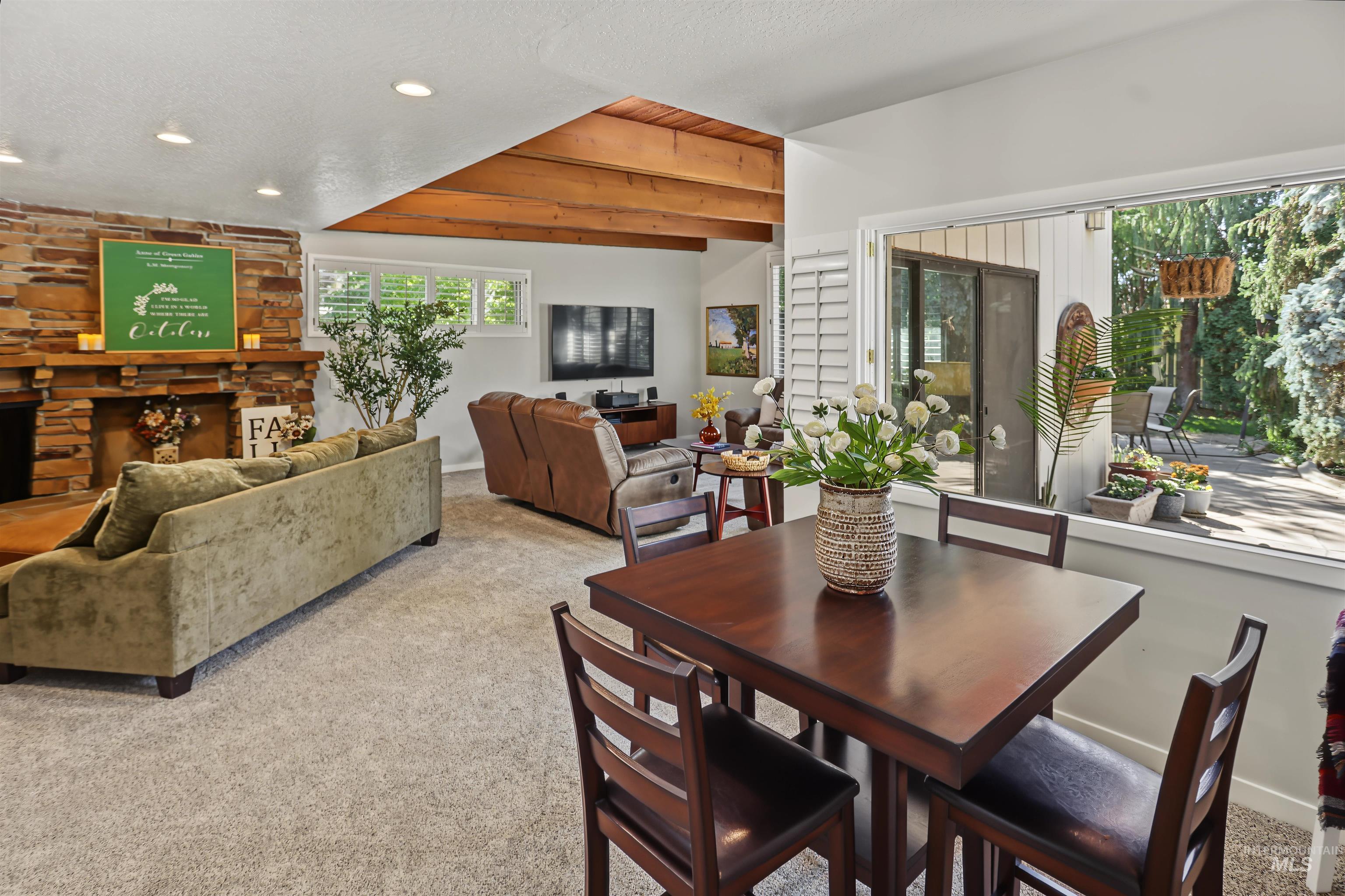 508 East Elm Avenue Parma, ID 83660 - Photo 15 of 50 Exposed wood beam ceiling, stone fireplace, recessed lighting, and expansive window with outdoor access