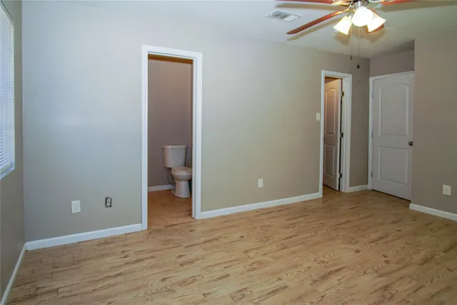 a view of an empty room with wooden floor and a bathroom