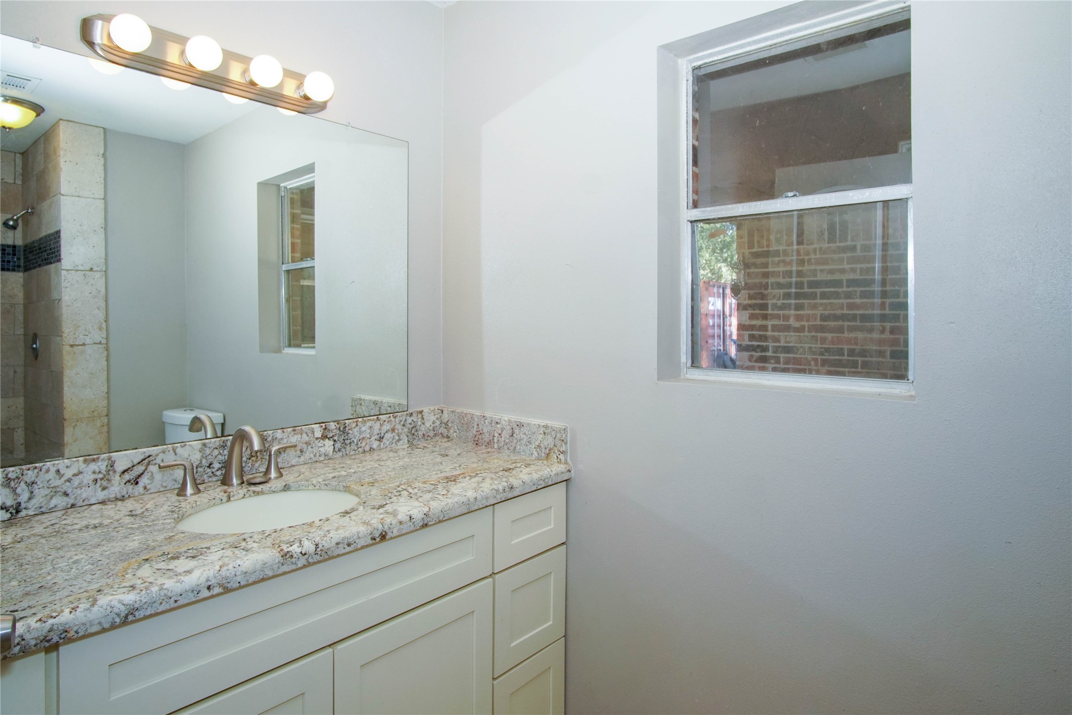 1926 16th Street Hempstead, TX 77445 - Photo 12 of 19 a bathroom with a granite countertop sink a mirror and a vanity