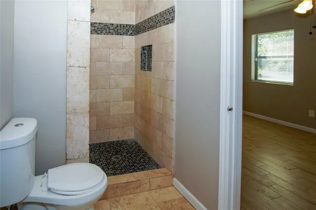 a bathroom with a toilet a window and shower