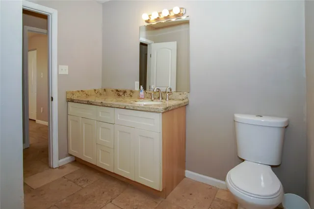 a bathroom with a granite countertop toilet sink and mirror