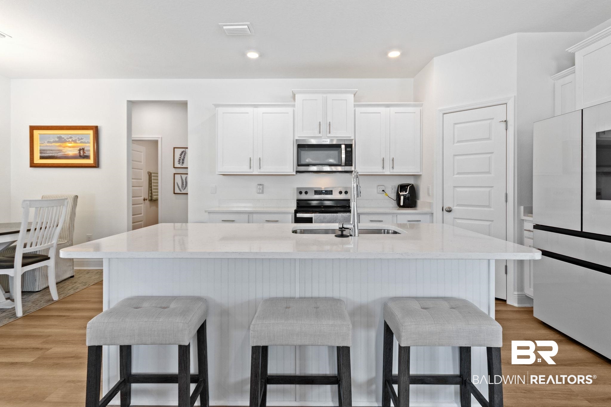 12919 Torrent Road Fairhope, AL 36532 - Photo 23 of 74 Kitchen with white cabinets, light stone countertops, a kitchen island with sink, stainless steel appliances, and light wood-style flooring