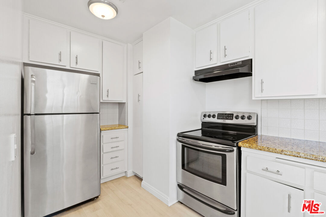10747 Wilshire Boulevard, Unit 703 Los Angeles, CA 90024 - Photo 5 of 16 a kitchen with stainless steel appliances white cabinets and a stove