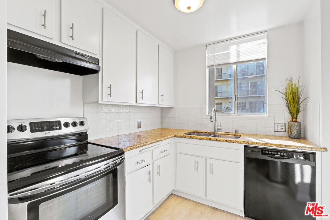 10747 Wilshire Boulevard, Unit 703 Los Angeles, CA 90024 - Photo 6 of 16 a kitchen with stainless steel appliances a sink dishwasher a stove and white cabinets