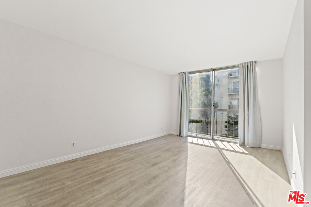 10747 Wilshire Boulevard, Unit 703 Los Angeles, CA 90024 - Photo 8 of 16 a view of an empty room with wooden floor and a window