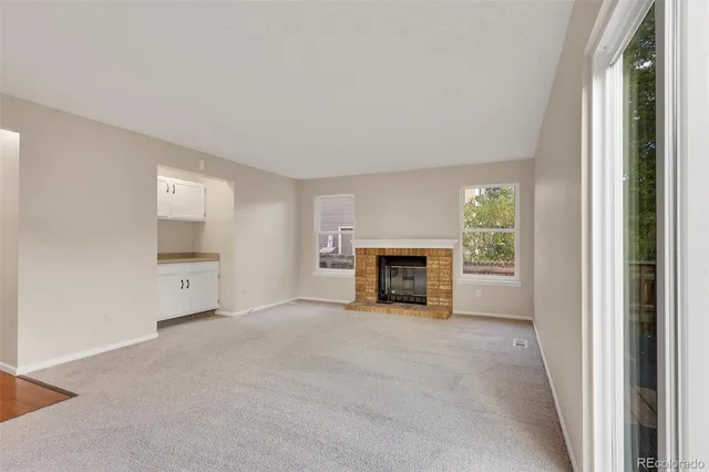 a view of an empty room with a window and a fireplace