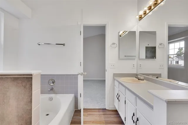 a bathroom with a bathtub a double vanity sink and a mirror