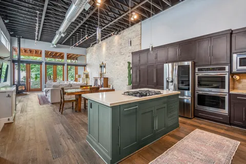 a kitchen with stainless steel appliances kitchen island granite countertop a sink stove and refrigerator