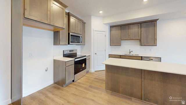 777 Pheasantbrook Drive, Unit 2B Centerville, UT 84014 - Photo 8 of 42 Kitchen featuring an eat-at island, stainless steel appliances, wood-finish flooring, recessed lighting, and a pantry door