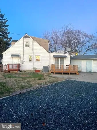 a view of a white house next to a yard with a large tree