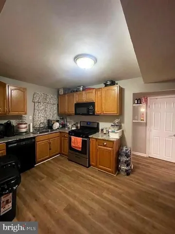 a large kitchen with stainless steel appliances granite countertop a stove and a wooden floors