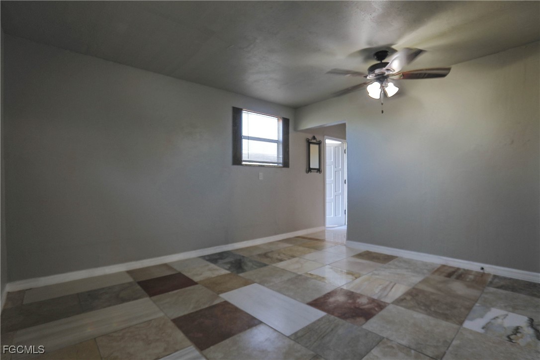 907 Laredo Avenue Lehigh Acres, FL 33936 - Photo 11 of 13 an empty room with a chandelier fan and windows