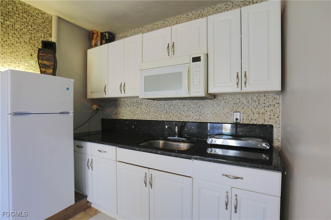 907 Laredo Avenue Lehigh Acres, FL 33936 - Photo 12 of 13 a kitchen with granite countertop white cabinets and stainless steel appliances