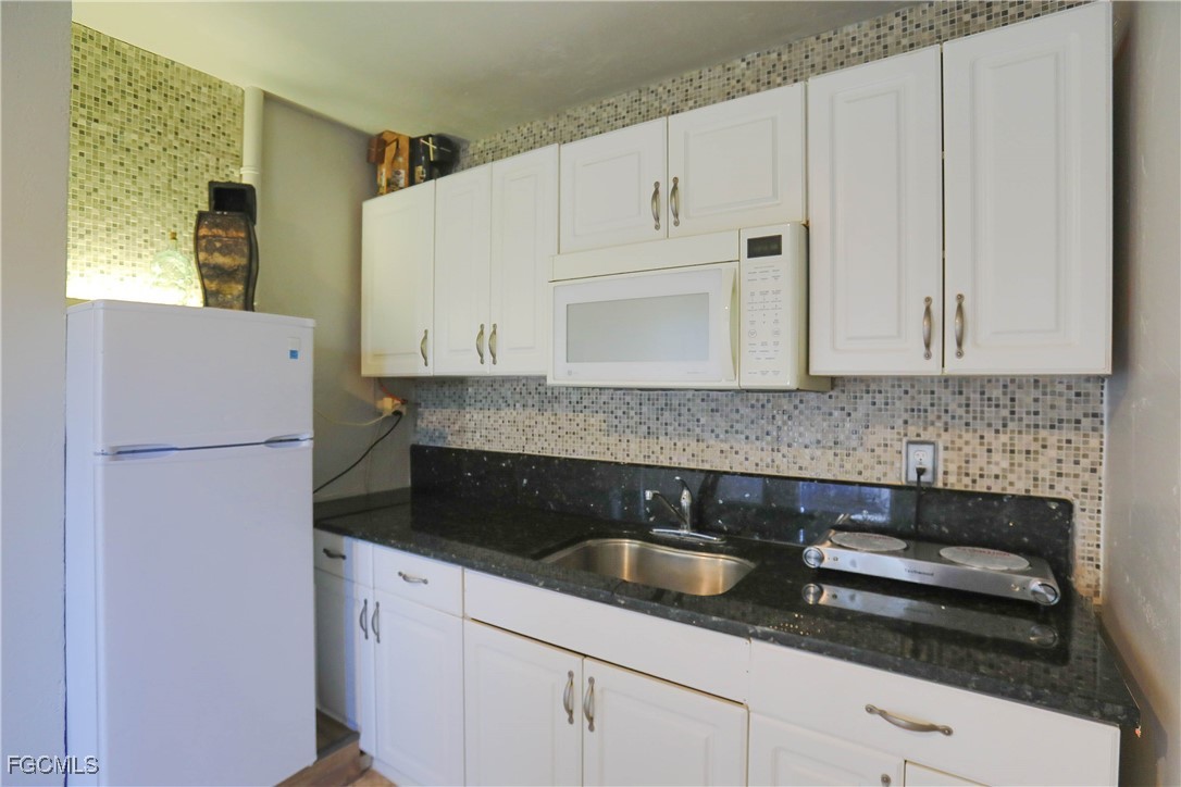 907 Laredo Avenue Lehigh Acres, FL 33936 - Photo 7 of 13 a kitchen with granite countertop white cabinets and white appliances