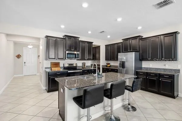 a kitchen with stainless steel appliances granite countertop a stove top oven a sink dishwasher a dining table and chairs