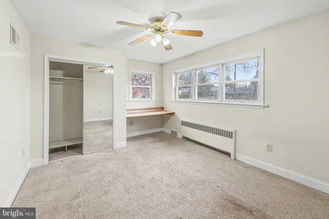 an empty room with chandelier fan and windows