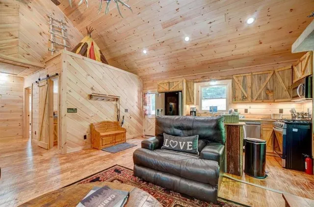 a living room with stainless steel appliances furniture and a kitchen view
