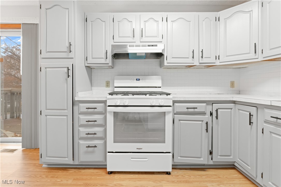 1574 Faye Road Akron, OH 44306 - Photo 10 of 45 Kitchen with white gas range, decorative backsplash, light hardwood / wood-style flooring, and white cabinets