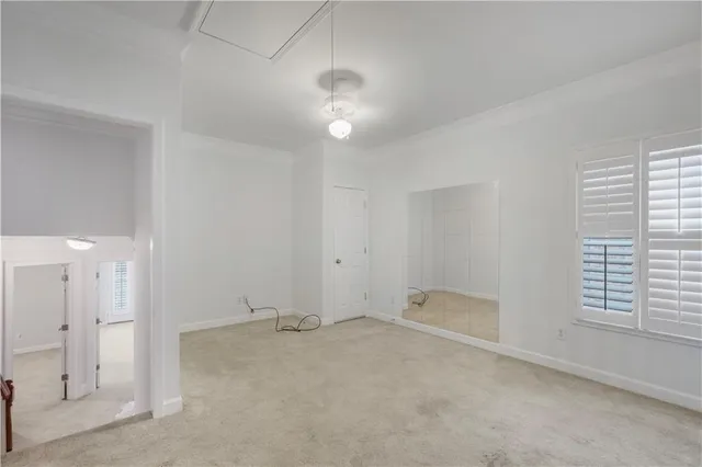 an empty room with chandelier fan and windows