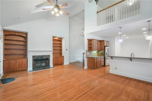 a view of a livingroom with a fireplace a ceiling fan and windows